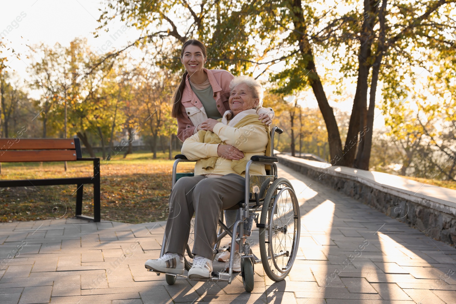 Photo of Caregiver with elderly woman in wheelchair at park