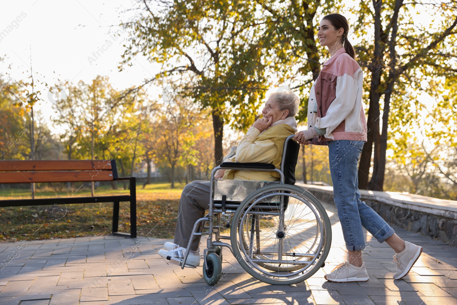 Photo of Caregiver with elderly woman in wheelchair at park