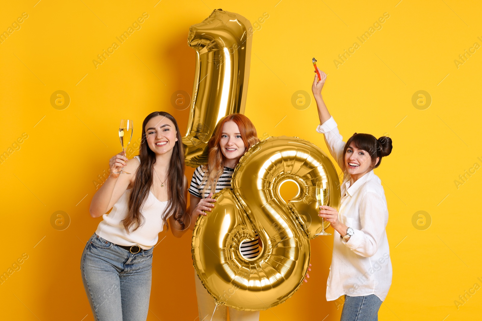 Photo of Coming of age party - 18th birthday. Group of young women celebrating with number shaped balloons on yellow background