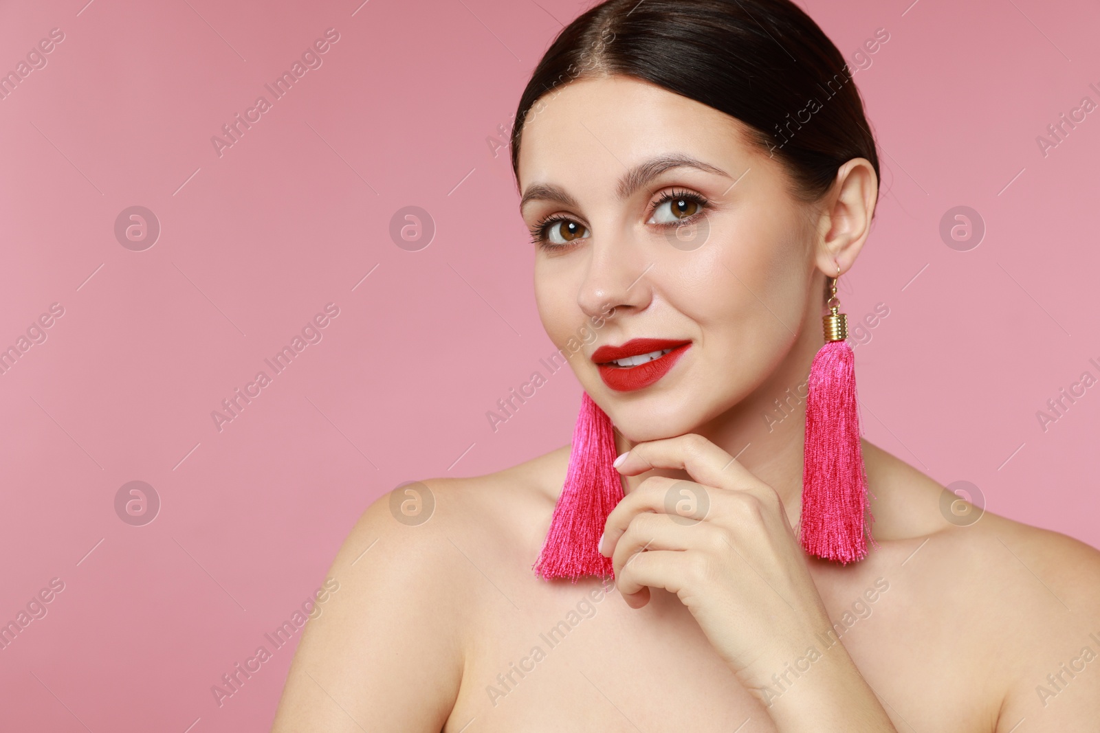 Photo of Beautiful young woman wearing stylish earrings on pink background. Space for text