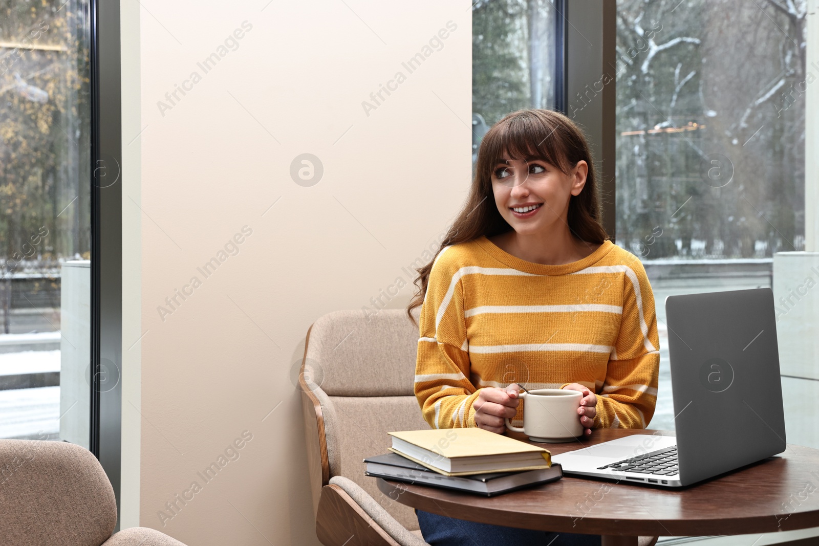 Photo of Smiling woman with laptop having coffee break at table in cafe. Space for text