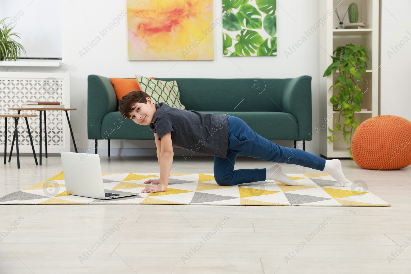 Photo of Boy having training with online coach via laptop at home