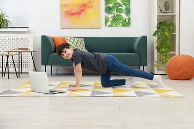 Boy having training with online coach via laptop at home