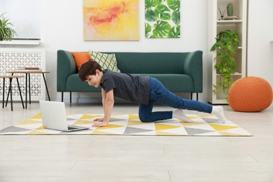 Photo of Boy having training with online coach via laptop at home