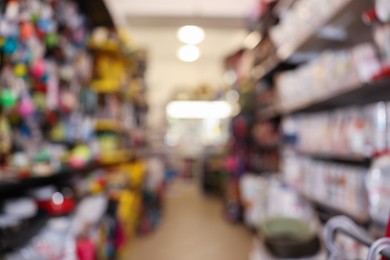 Photo of Blurred view of shelves with different products in pet shop