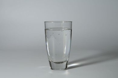 Photo of Refreshing soda water in glass on grey background