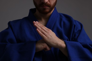 Photo of Karate fighter in uniform on grey background, closeup