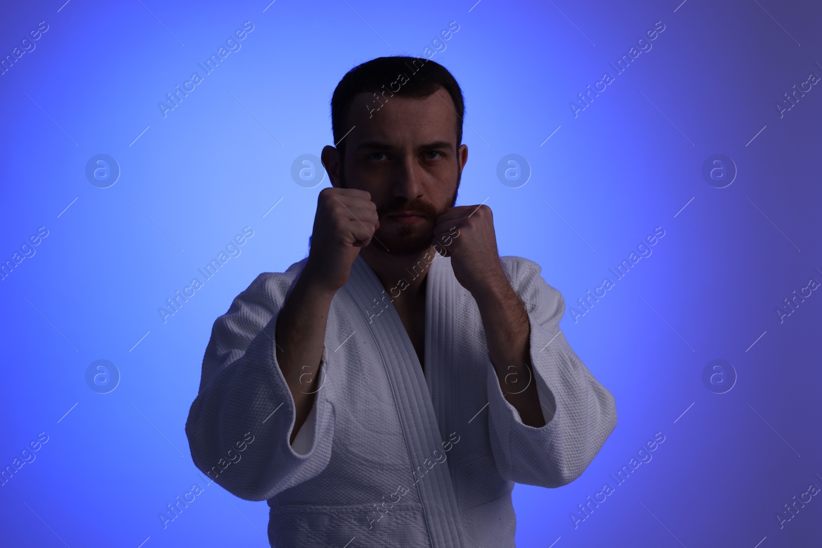 Photo of Karate fighter in uniform on blue background