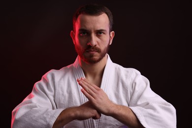 Photo of Karate fighter wearing uniform in color light against black background