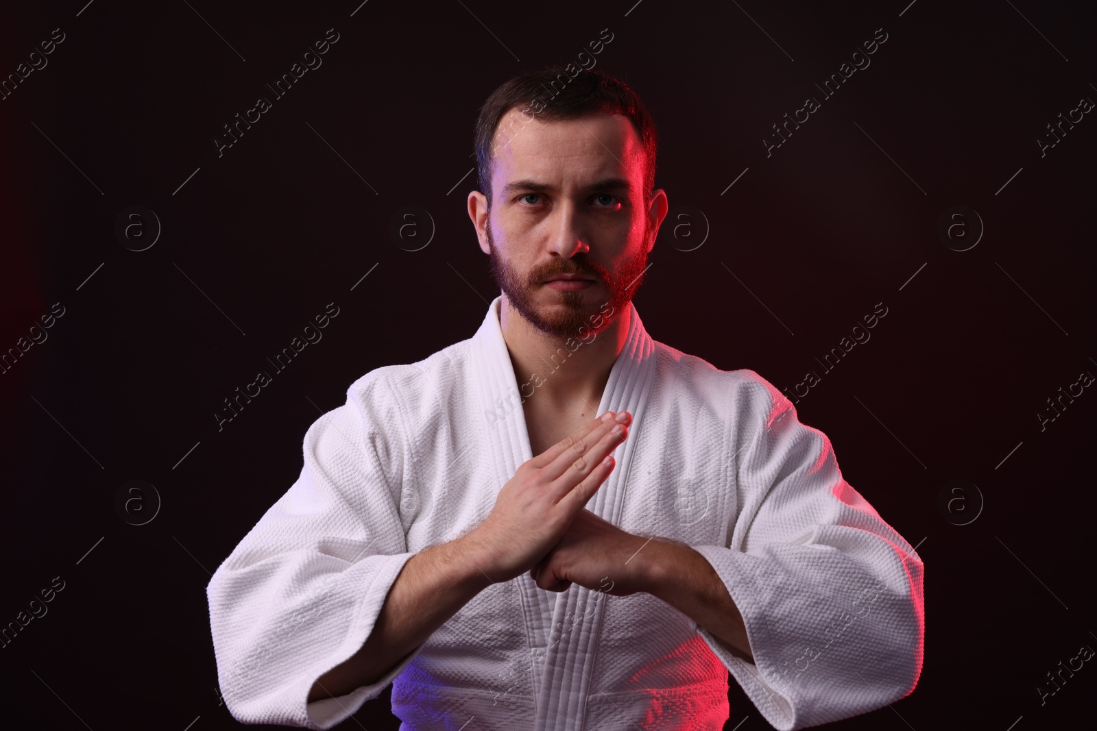 Photo of Karate fighter wearing uniform in color light against black background