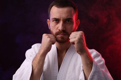 Photo of Karate fighter in color lights and smoke against black background