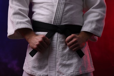 Photo of Karate fighter in kimono in color lights and smoke, closeup