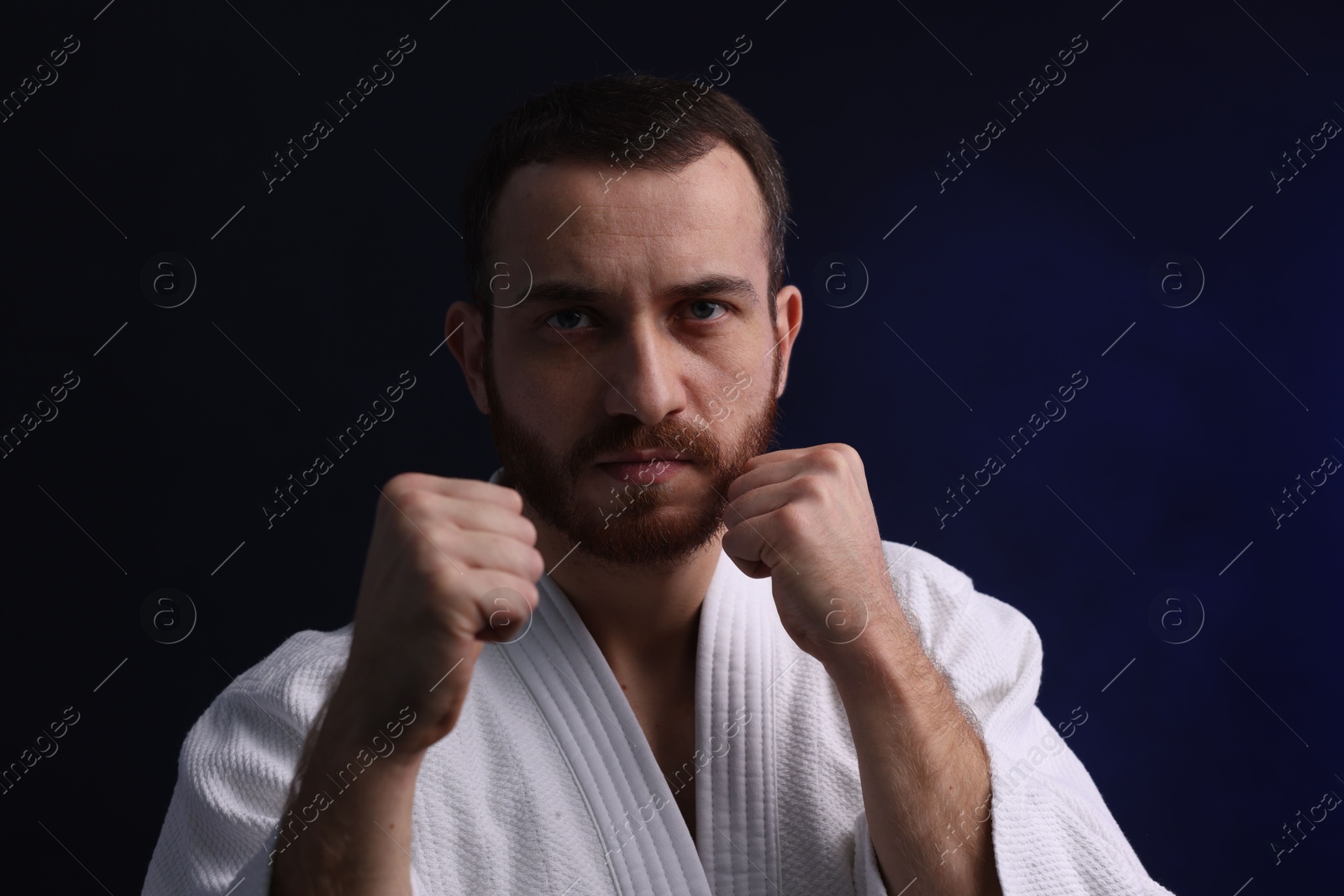 Photo of Karate fighter in uniform on dark background