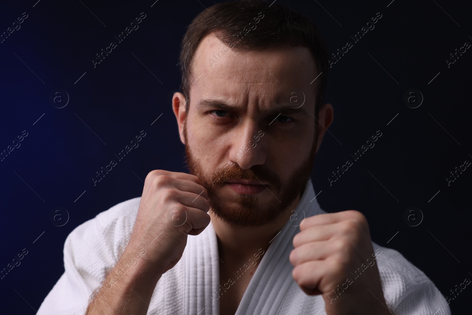 Photo of Karate fighter in uniform on dark background