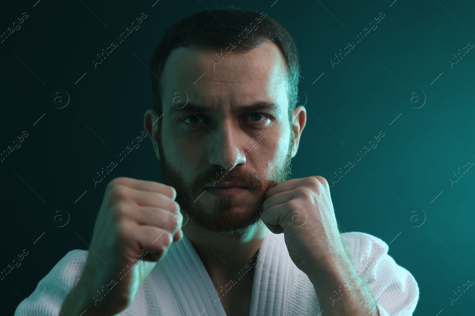 Photo of Karate fighter wearing uniform in color lights, closeup