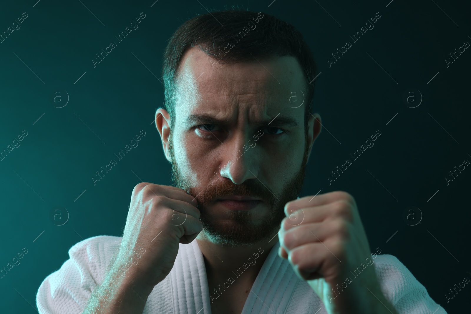 Photo of Karate fighter wearing uniform in color lights, closeup