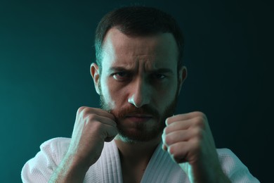 Photo of Karate fighter wearing uniform in color lights, closeup