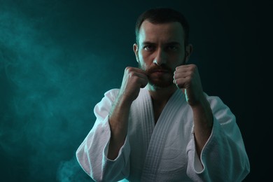 Photo of Karate fighter wearing uniform in color lights and smoke