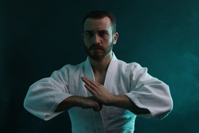 Photo of Karate fighter wearing uniform in color lights and smoke