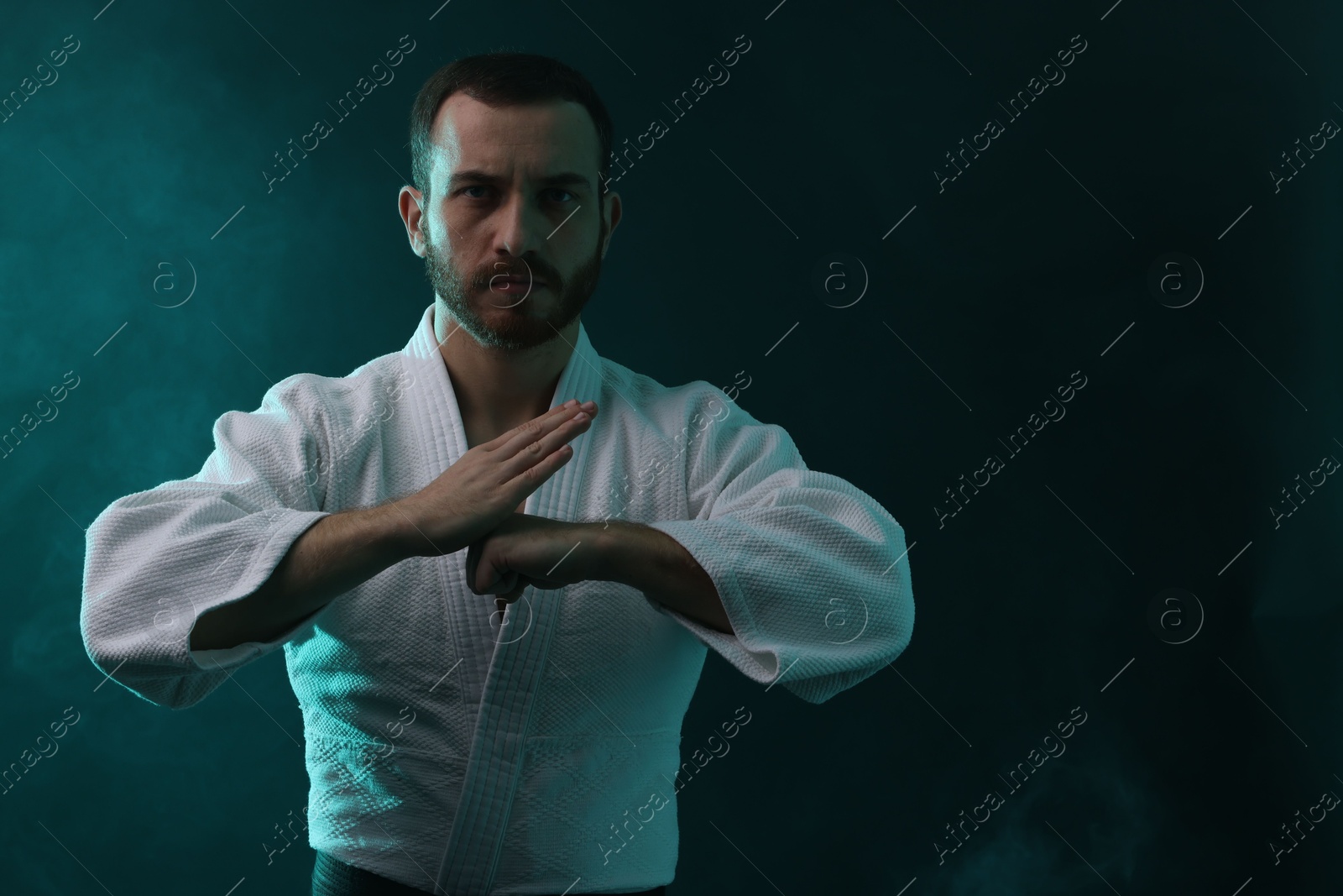 Photo of Karate fighter wearing uniform in color lights and smoke