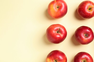 Many red apples on beige background, flat lay. Space for text