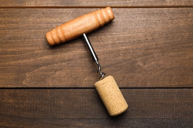 Photo of Corkscrew and cork on wooden table, top view