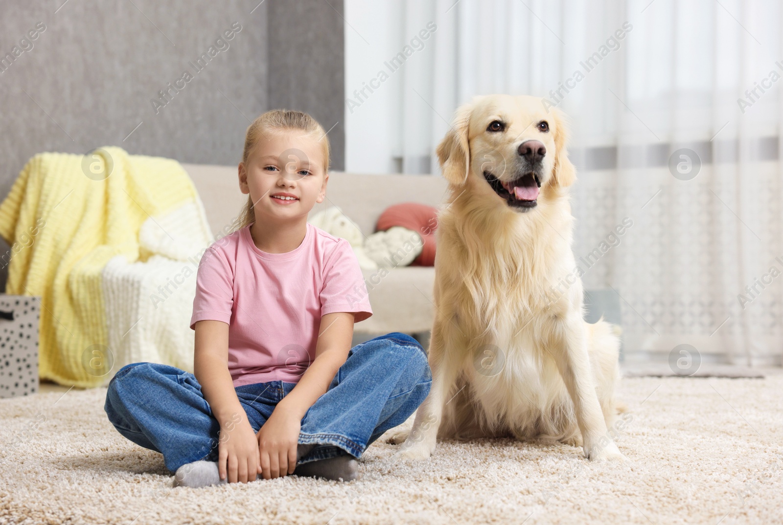 Photo of Girl with her cute Golden Retriever dog on rug at home