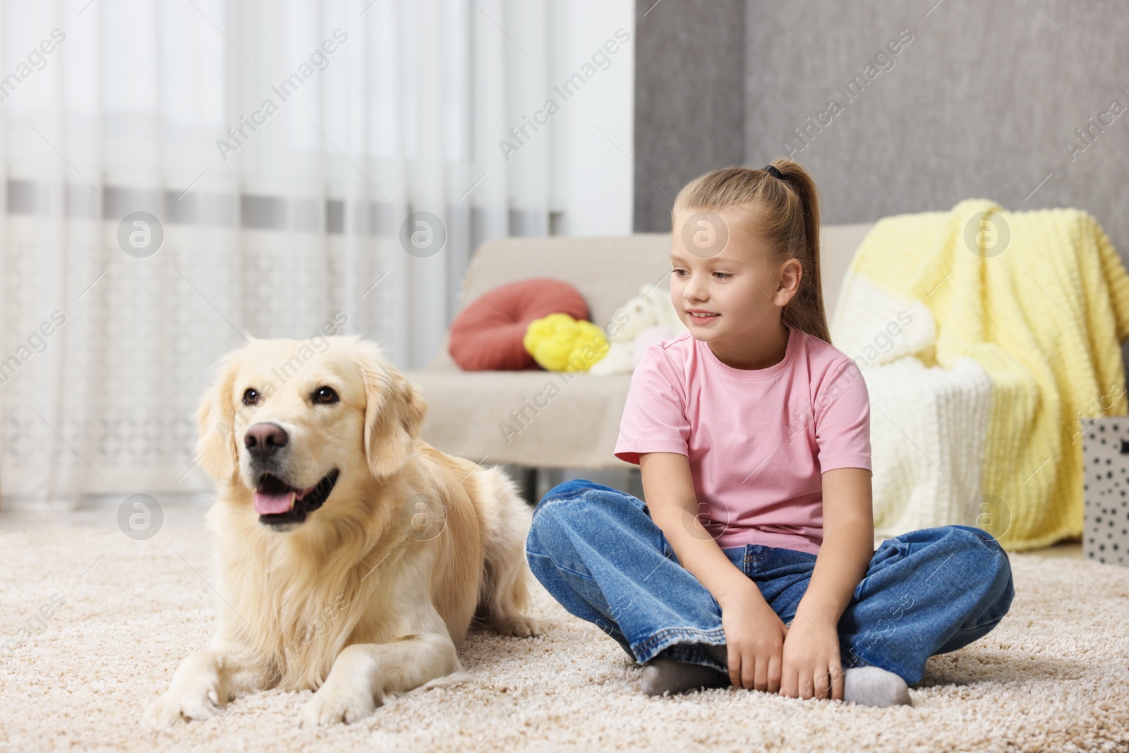 Photo of Girl with her cute Golden Retriever dog on rug at home