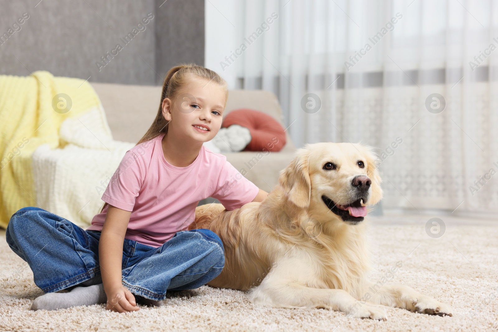 Photo of Girl with her cute Golden Retriever dog on rug at home