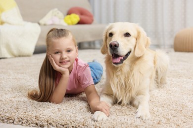 Photo of Girl with cute Golden Retriever dog lying on rug at home