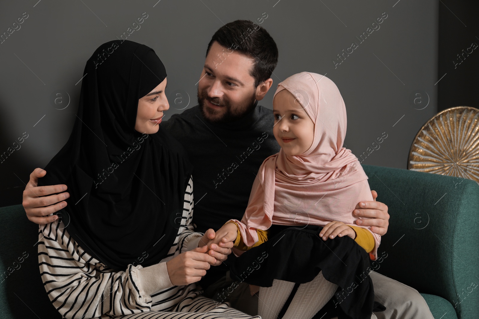 Photo of Happy Muslim family sitting on sofa at home