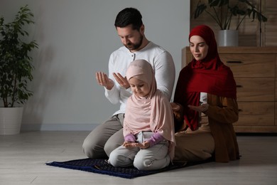 Photo of Muslim family praying on mat at home