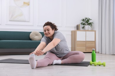 Photo of Plus size woman stretching during fitness training at home