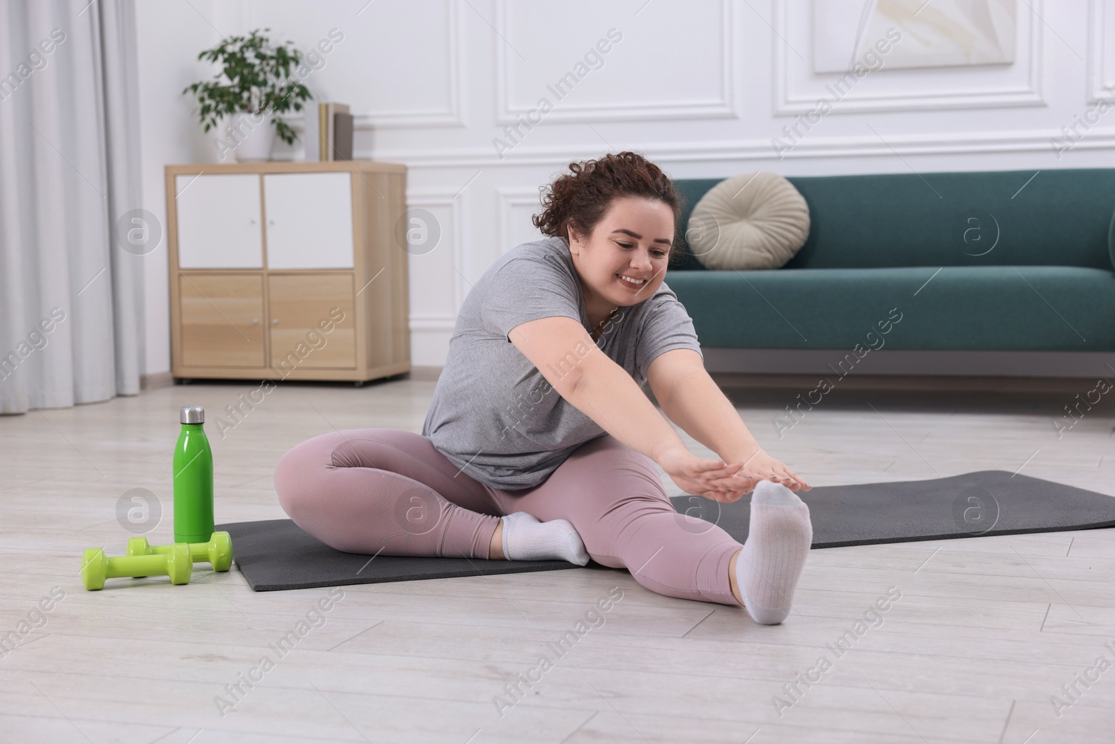 Photo of Plus size woman stretching during fitness training at home