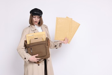 Photo of Surprised postwoman with bag and envelopes on white background. Space for text