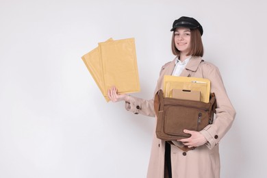 Photo of Happy postwoman with bag and envelopes on white background. Space for text