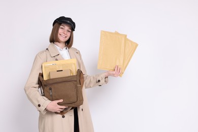 Photo of Happy postwoman with bag and envelopes on white background. Space for text