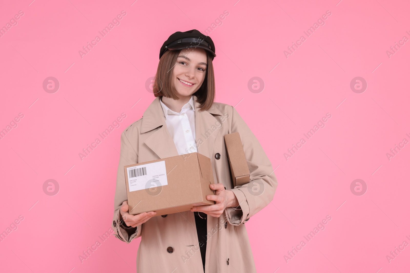 Photo of Happy postwoman with parcels on pink background