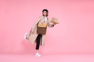 Photo of Happy postwoman with bag and parcels on pink background