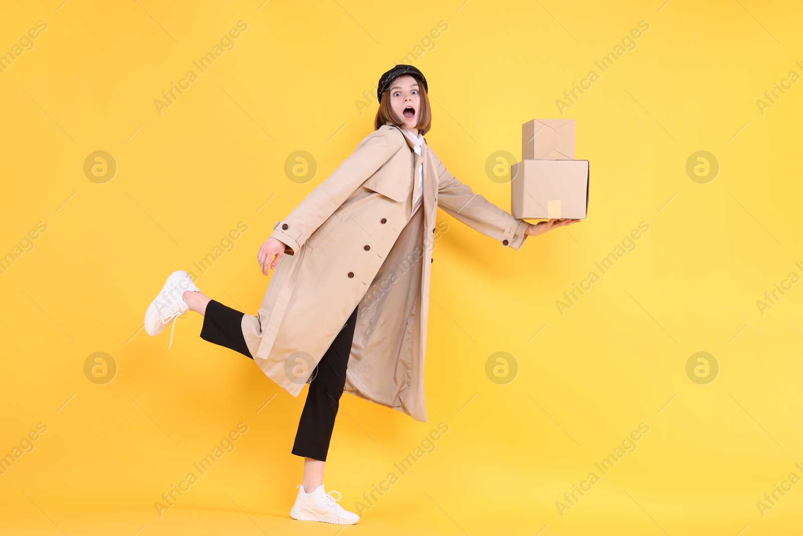 Photo of Emotional postwoman with parcels on yellow background