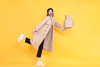 Photo of Emotional postwoman with parcels on yellow background