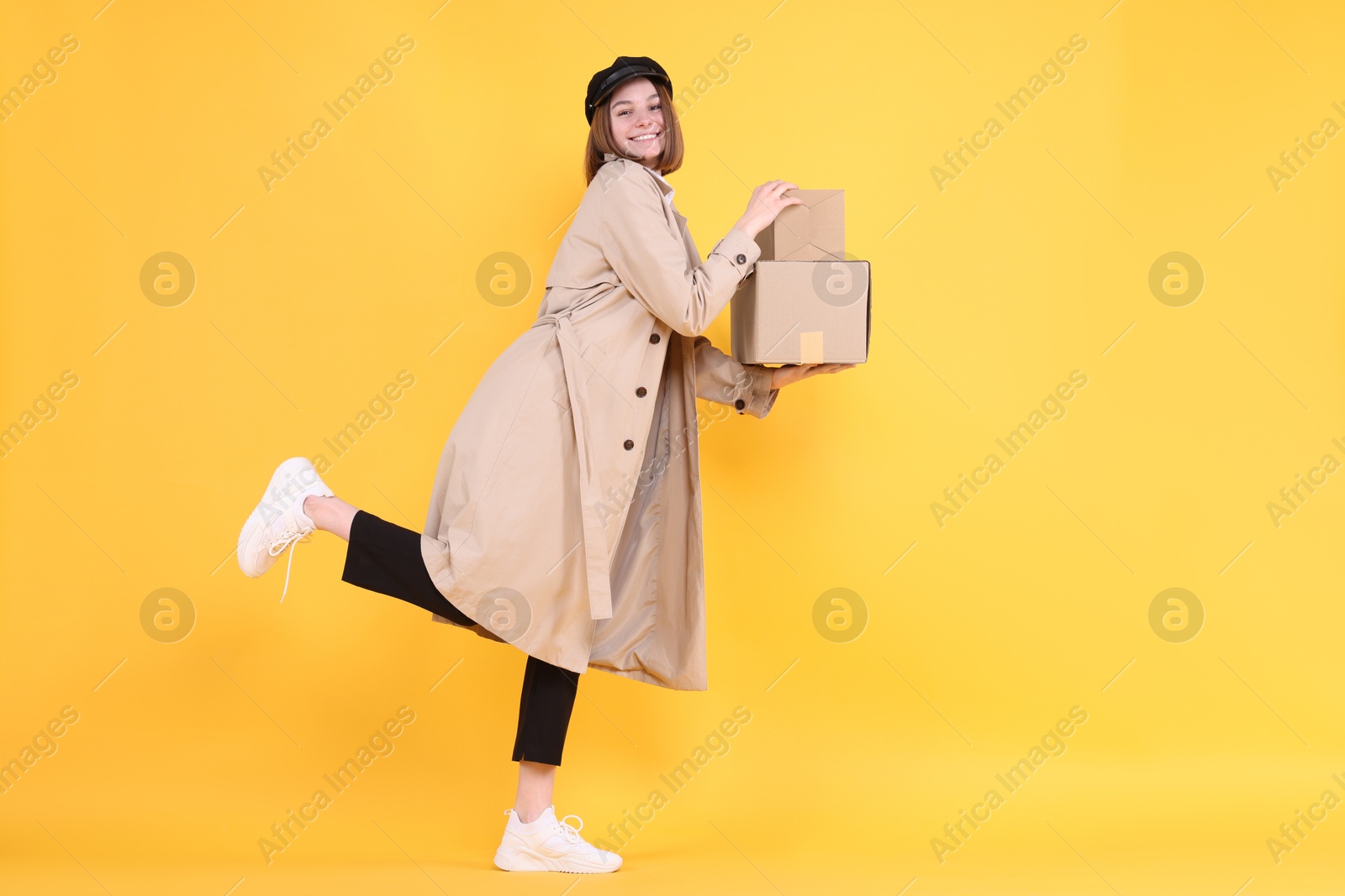 Photo of Happy postwoman with parcels on yellow background