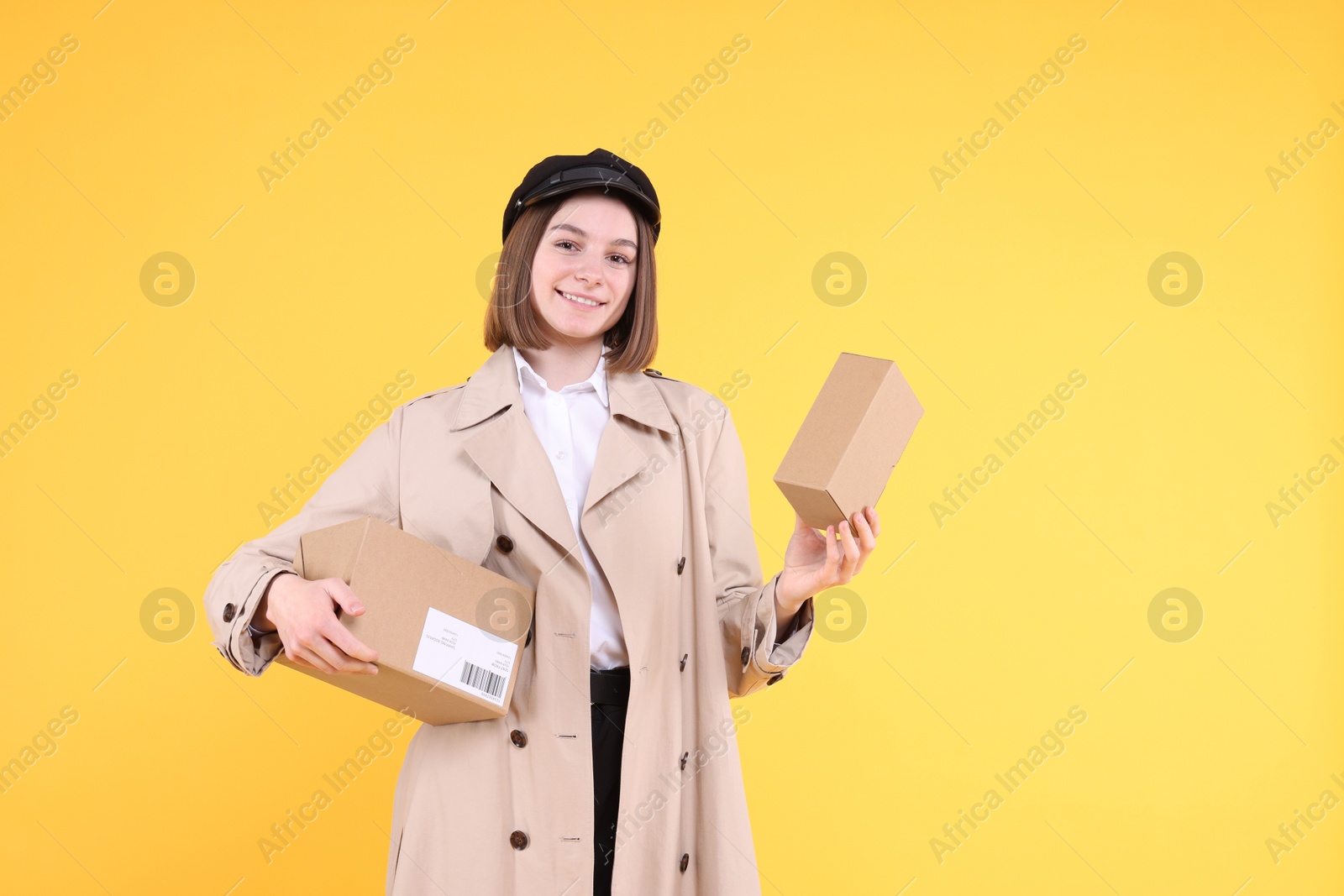 Photo of Happy postwoman with parcels on yellow background. Space for text