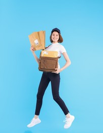 Photo of Happy postwoman with bag and envelopes jumping on light blue background