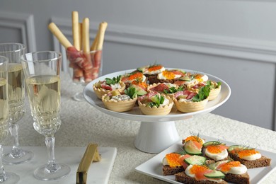 Photo of Many different tasty canapes and wine on white table