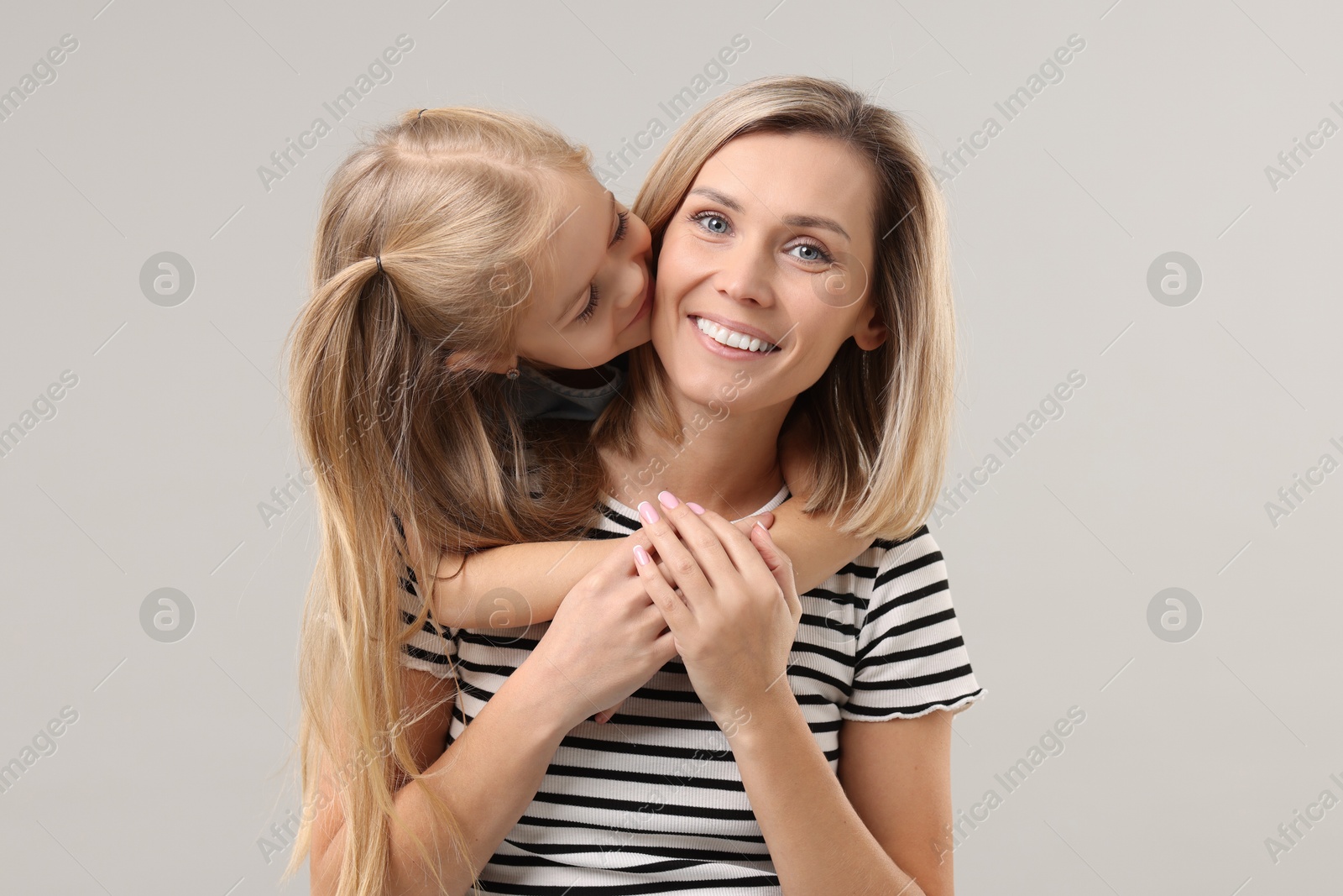 Photo of Cute little girl with her mom on gray background. Happy Mother's Day