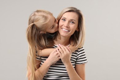 Cute little girl with her mom on gray background. Happy Mother's Day