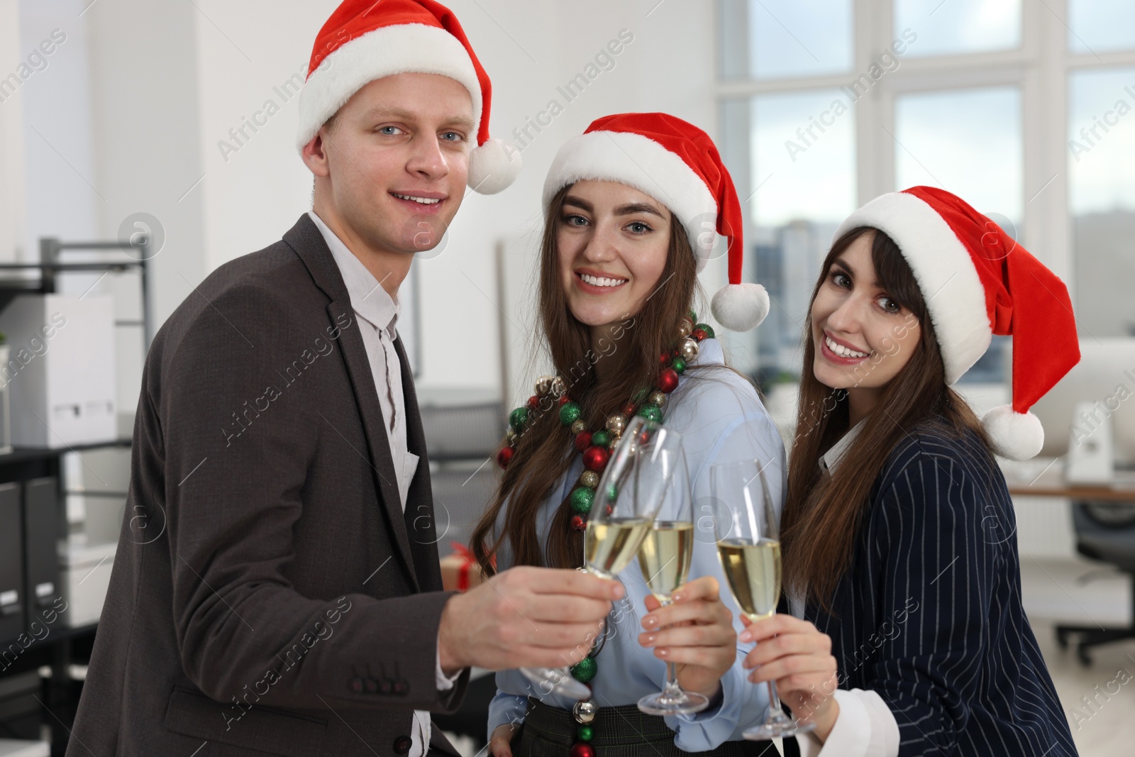 Photo of Happy coworkers clinking glasses of wine during office Christmas party