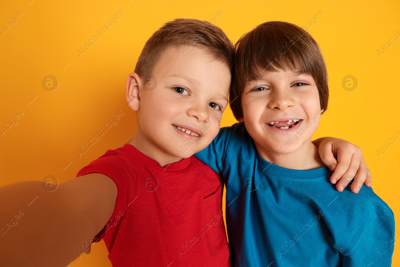 Photo of Cute brothers taking selfie on orange background