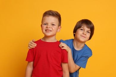 Photo of Portrait of cute brothers on orange background